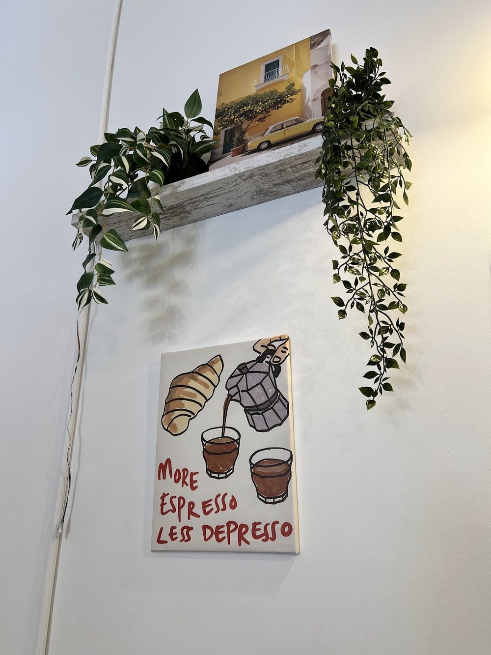 A corner of the café wall with a shelf, trailing ivy and a hand-lettered print