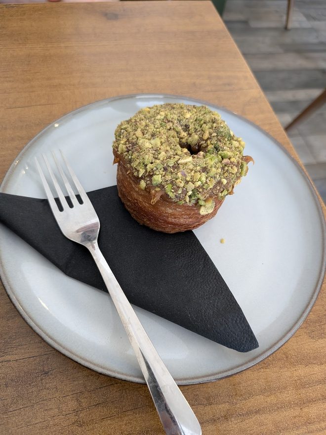 A pistachio-topped cruffin on a white plate