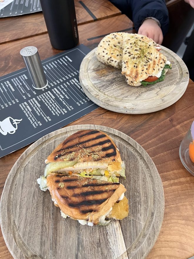 A bagel with cream cheese and a panini plated on a dark table